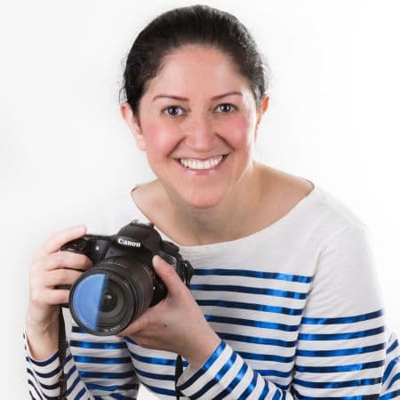 Sepideh Maleki holding a Canon camera, smiling against a white background.